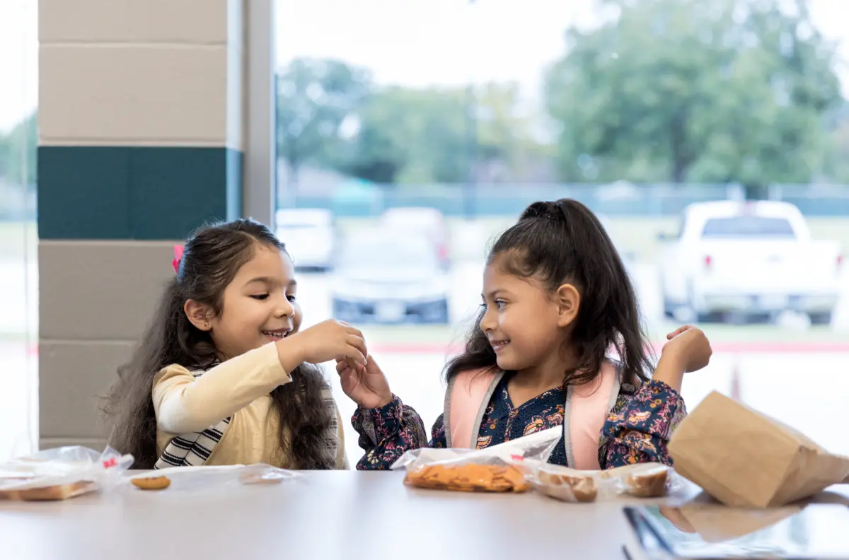 Twin sisters share lunch in the school cafeteria