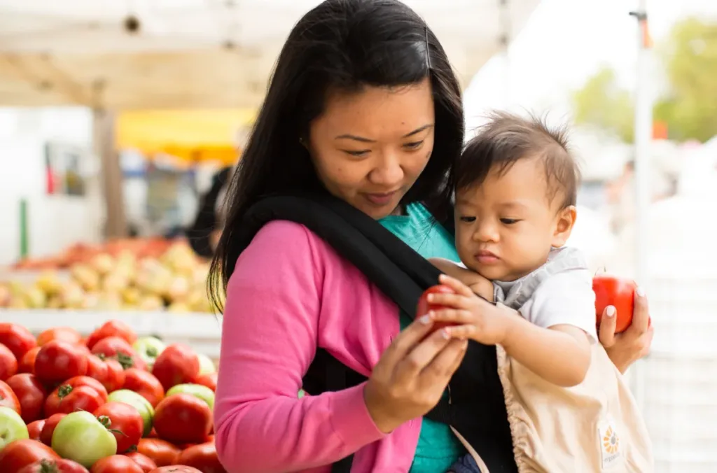 A mother and child select apples from a farmers market