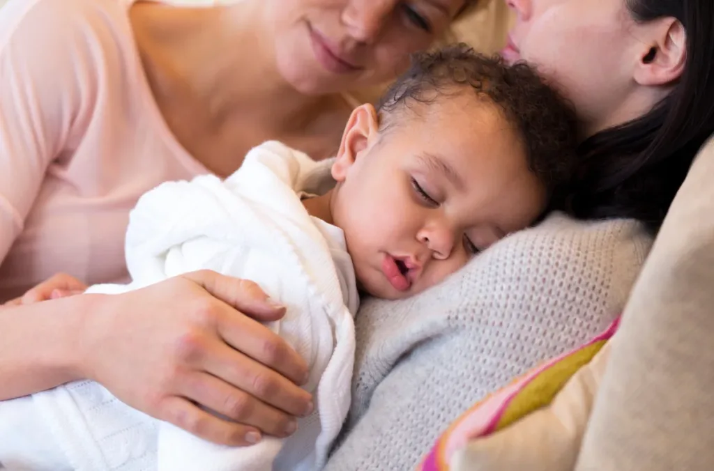 Two moms nap alongside their newborn